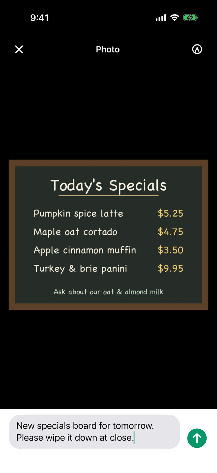 The photo screen on iPhone: the Photo title with the close button and the pencil for editing, a photo of a chalk specials board, and the caption New specials board for tomorrow. Please wipe it down at close. with the send arrow